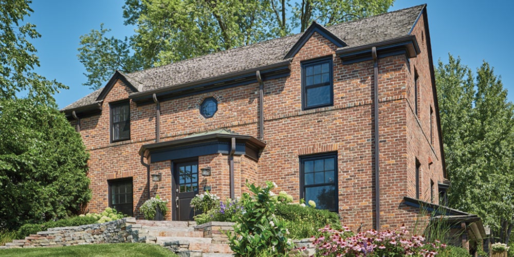 A classic brick home with black double hung windows.