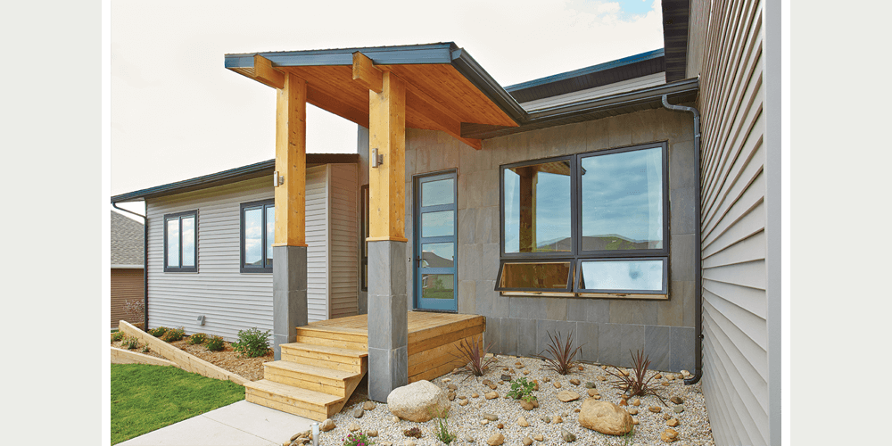 A one-story modern home with mixed materials incorporates casements, awnings and a wooden porch into the entryway.